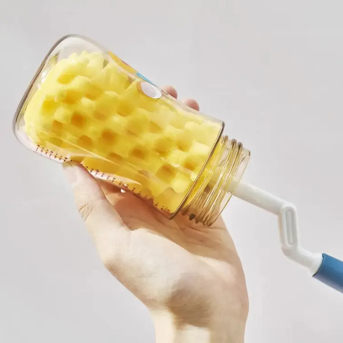 برس اسفنجی رووکو داخل شیشه شیر شیشه‌ای، دست در حال شست‌وشو